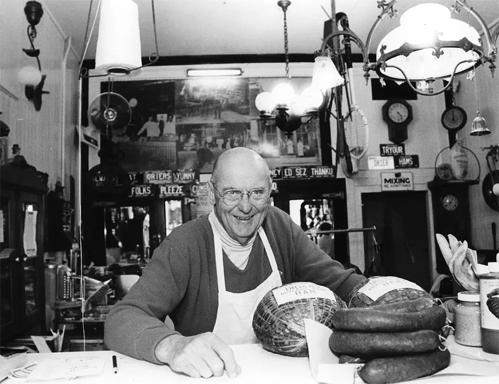 Vintage color photo of a Drier's Meat Market butcher in a white apron working in the shop's kitchen area